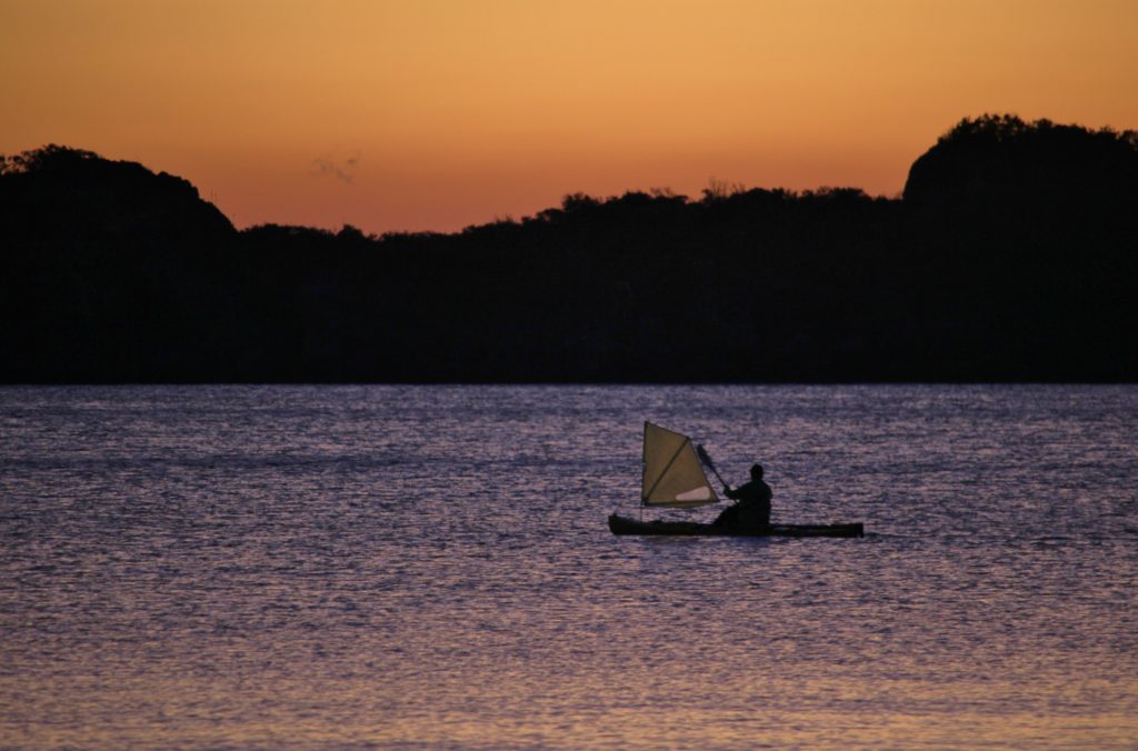 A small watercraft moves through the water at dawn in Cape Hillsborough, Australia