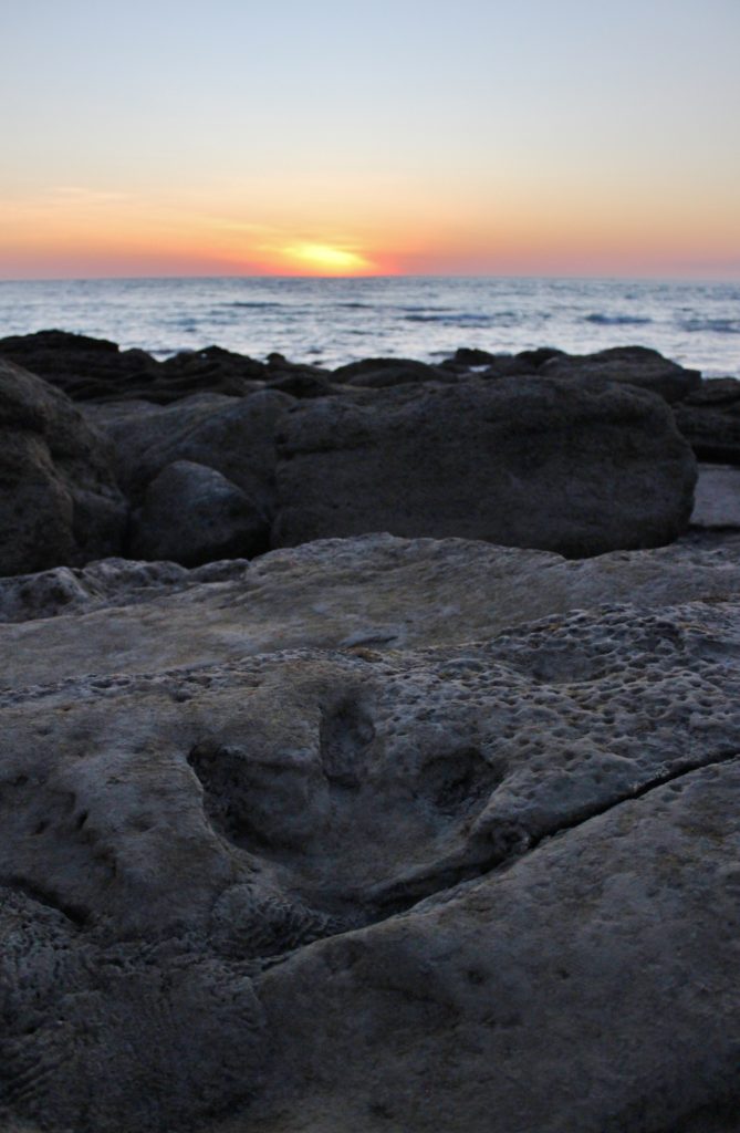 A dinosaur footprint with the setting sun at Broome, Australia