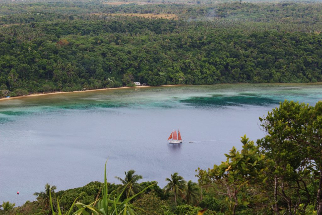 A sailboat moves through the harbour, Tonga