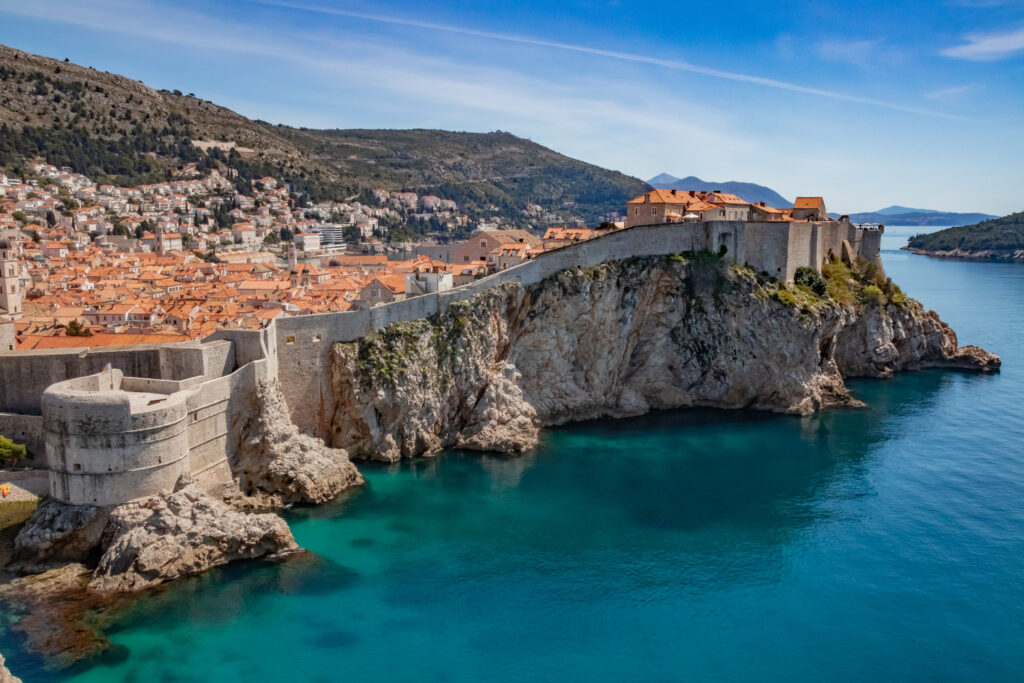 Dubrovnik's red rooftops sitting behind its walls on the top of a cliff