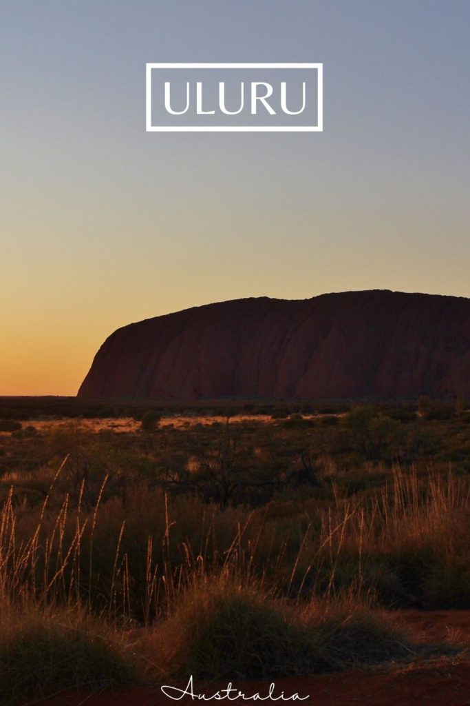 Sunrise over the huge silhouette of Uluru