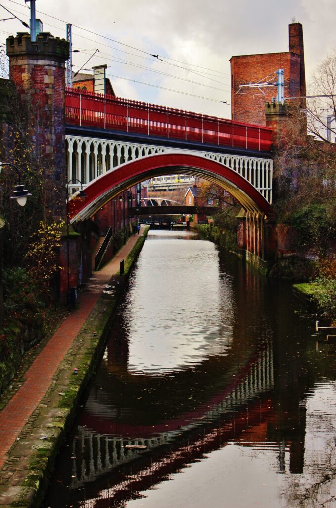 A red and white iron bridge over a canal in Manchester
