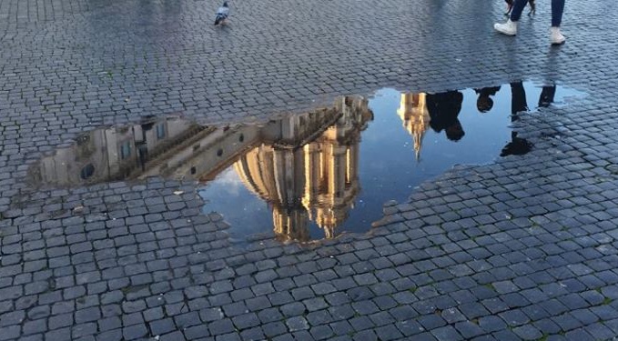A building in the Piazza Navona reflected in a puddle, Rome, Italy