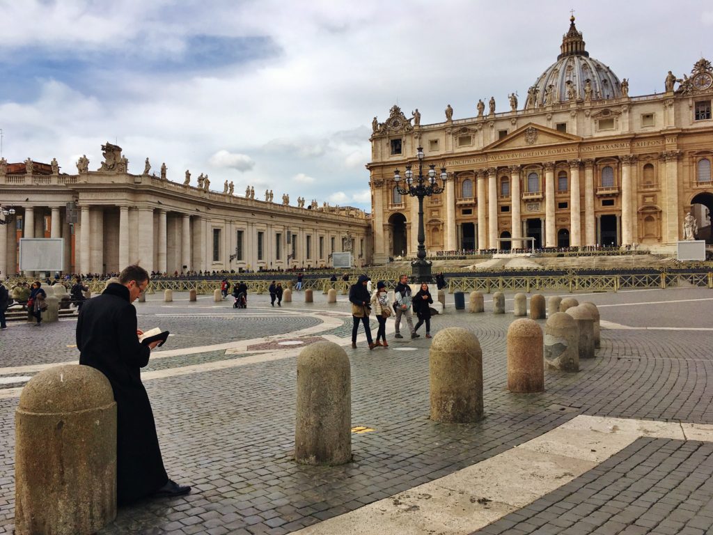 A priest reads a book in St. Peter's Square, Vatican City