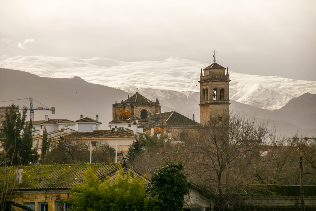 Snowy mountains behind the tower of a monastery in Granada, Spain