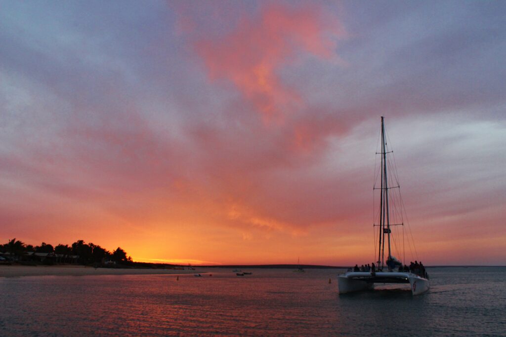 A yacht at anchor beneath a vibrant orange and red sunset