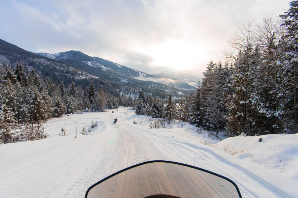 Riding down a snowy mountain slope on a snowmobile in BC, Canada