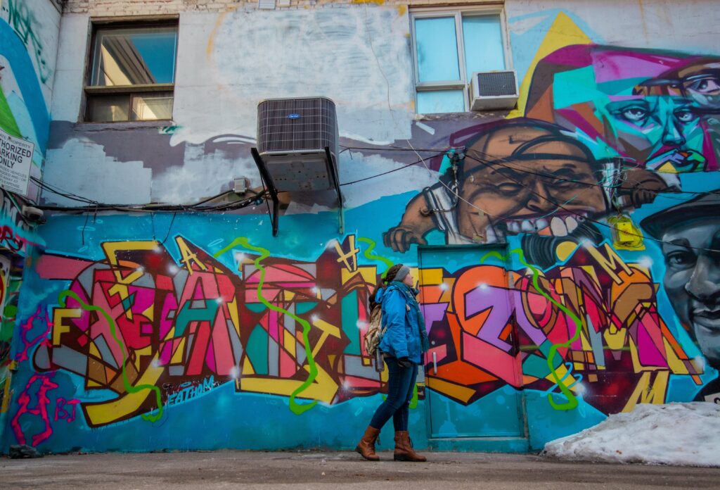 Walking in front of a large, colourful mural in Toronto's Rush Lane, one of the best photo spots in the city