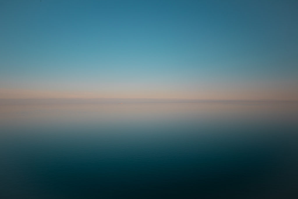 Blue sky merges into pink where the lake meets the horizon