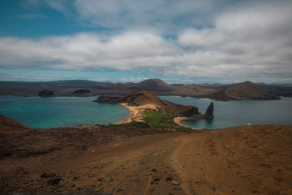 The view from the top of Bartolomé Island in the Galapagos, a narrow piece of land with a beach on either side and sharp Pinnacle Rock rising to the right