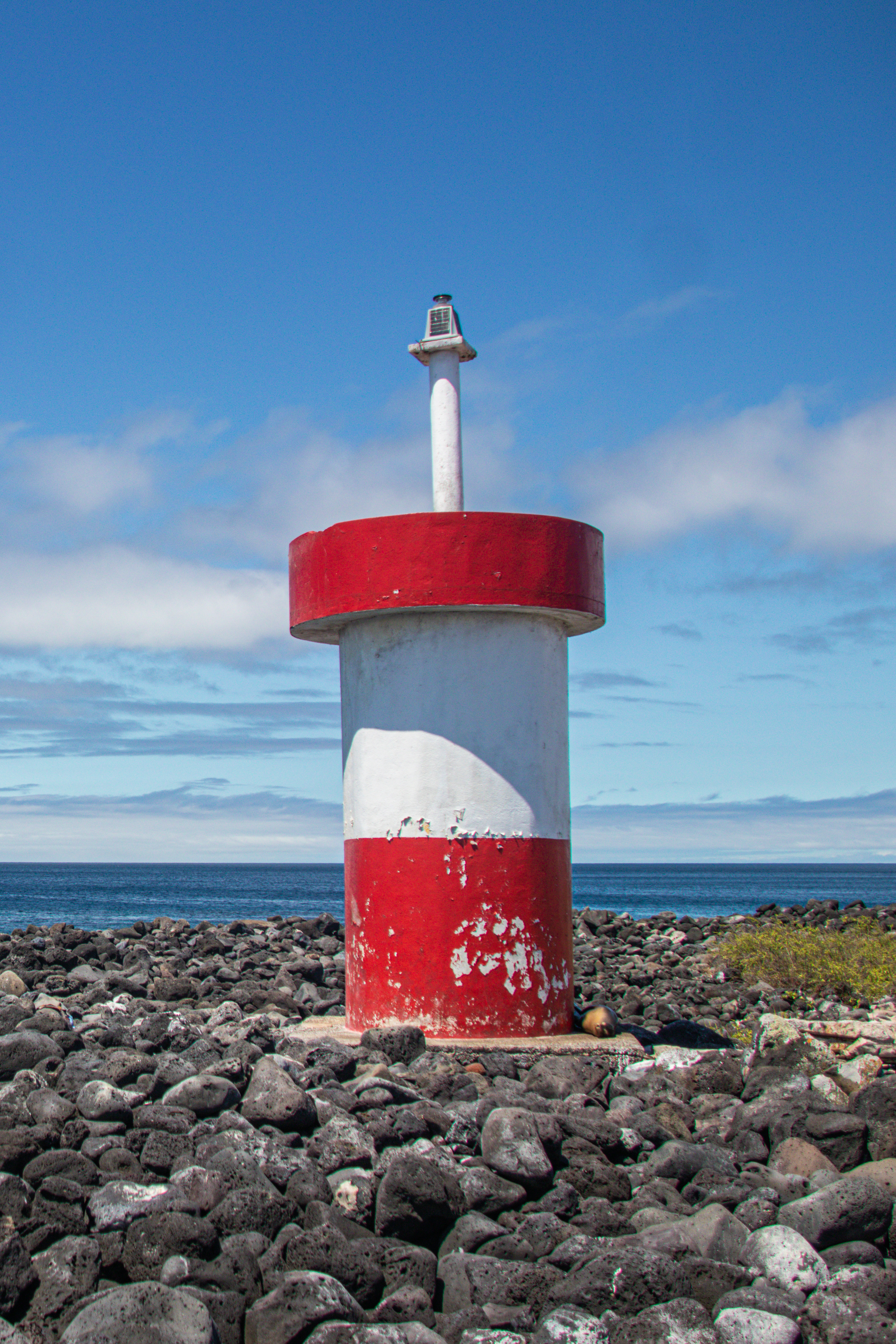 A small red and white lighthouse on the rocky coast of San Cristóbal in the Galapagos