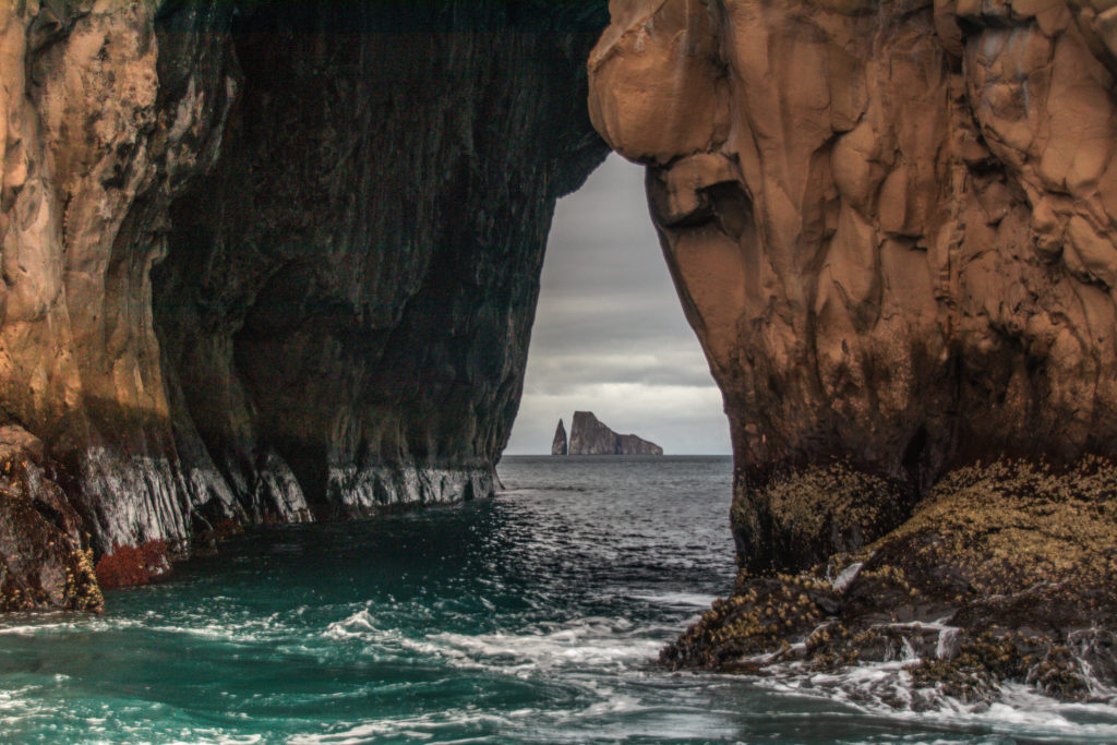 Kicker Rock seen through a sea arch on San Cristóbal, one of the best things to see while solo backpacking in the Galapagos
