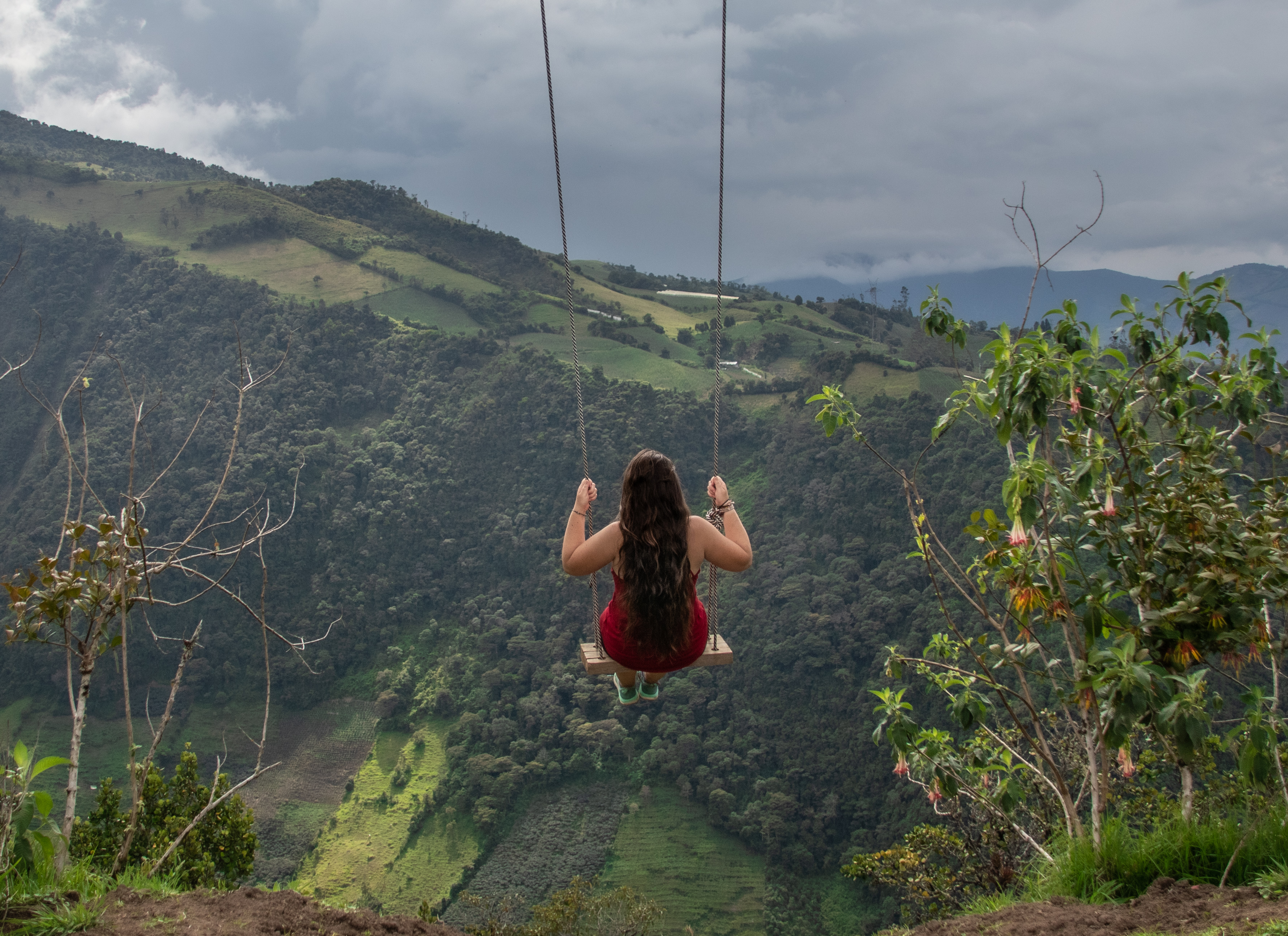 A girl sitting on a swing with mountains in the background, Banos, Ecuador
