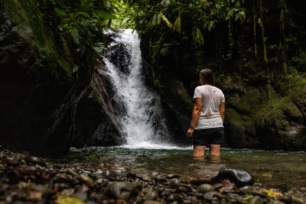 Standing knee-deep in the water below one of the many waterfalls in Mindo, one of the best places to visit on an Ecuador itinerary