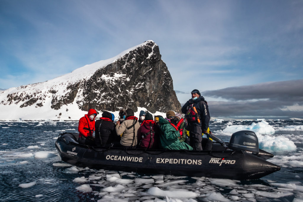 A zodiac full of passengers moves through ice-filled water on the Antarctic Peninsula