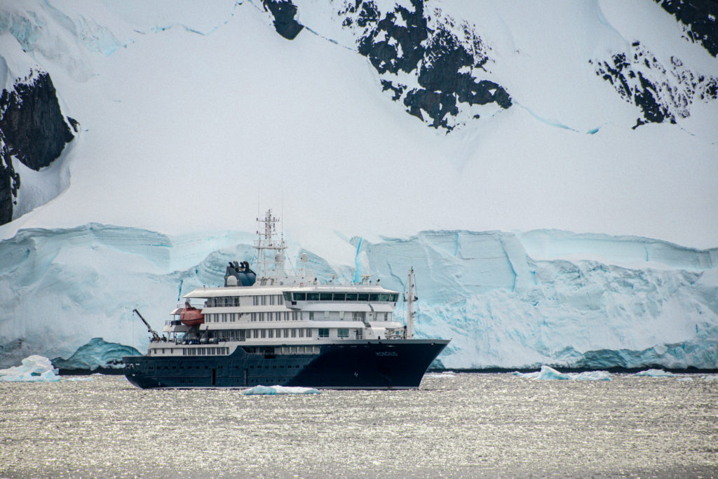 The MV Hondius sailing through Antarctic Waters, snow covered mountains in the background