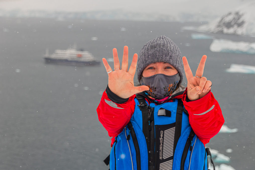 Seven outstreched fingers for seven continents! Bundled up in warm clothes against the chilly, misty bay in Antarctica.