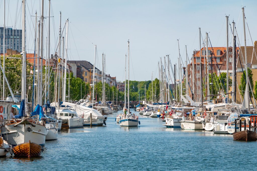 A yacht sails through a canal in Christianshavn, surrounded by other boats