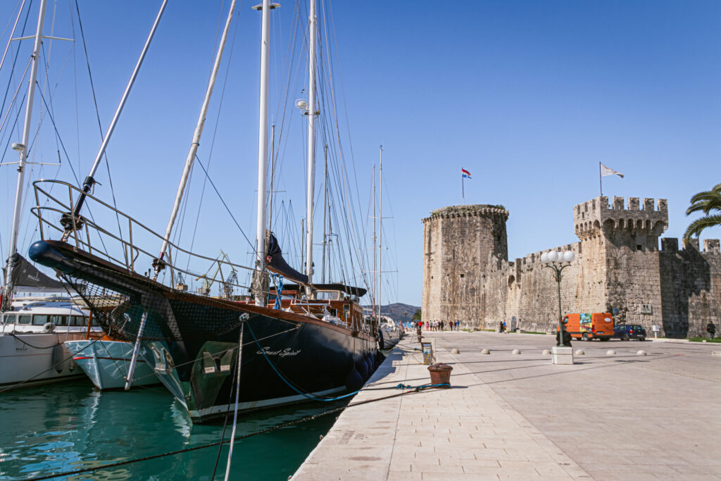 A large yacht is moored at Trogir, with the Kamerlengo Fortress in the background
