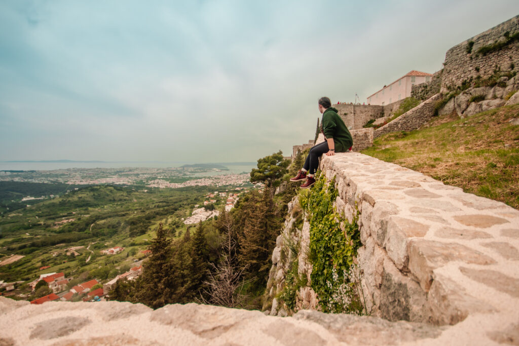 Sitting on the wall looking at the view from Klis Fortress, a great place to spend one of your days in Split