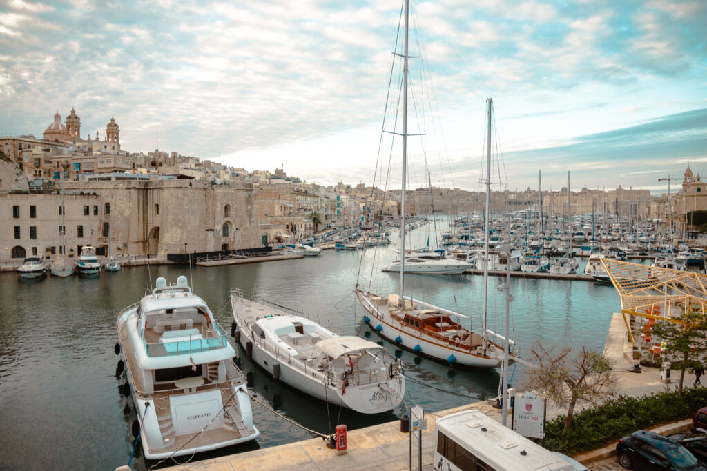 A large number of yachts sit in the water between two peninsulas of the Three Cities in Malta