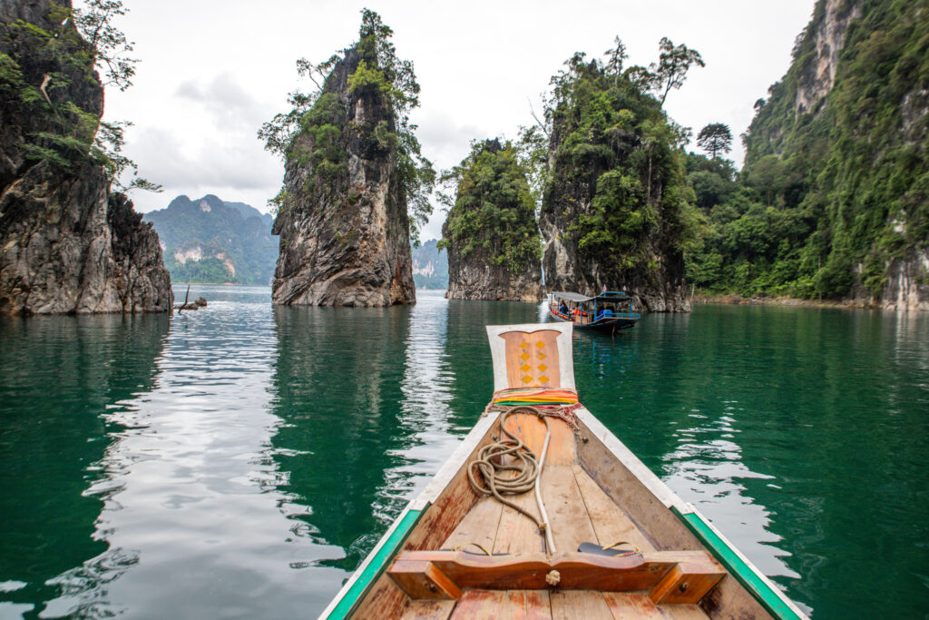 Limestone pillars and cliffs rising from the lake, with the prow of a boat in the foreground