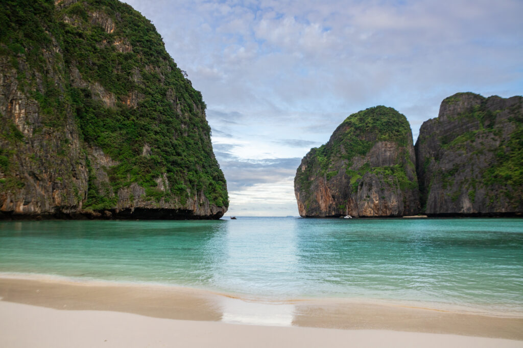 The clear water of Maya Bay, with the gap between the tall cliffs opening to the sea