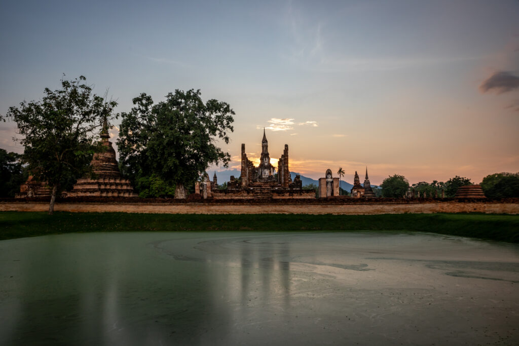 The sun setting behind the silhouette of Wat Mahathat in Sukhothai