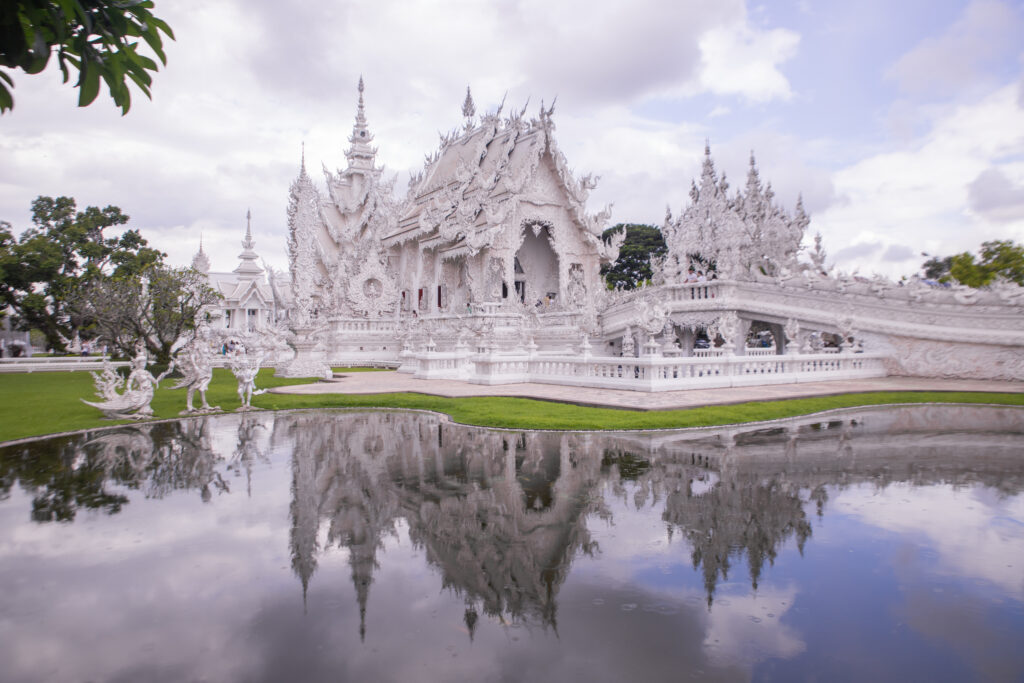 The White Temple near Chiang Rai reflected perfectly in its surrounding pools of water