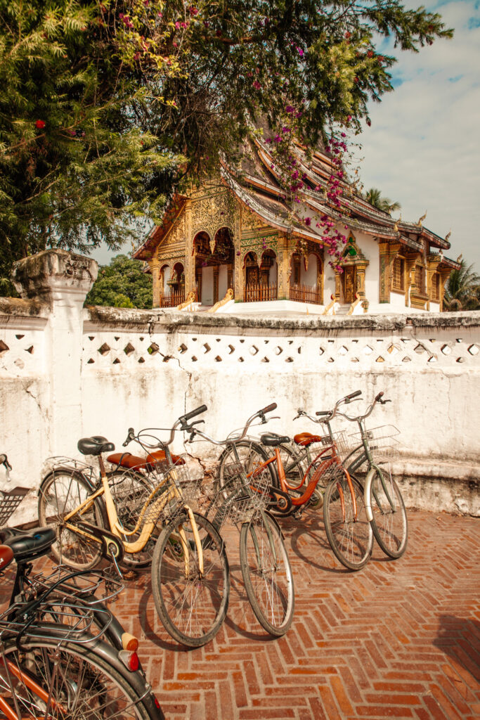 A row of bicycles parked by a white wall in front of a temple building