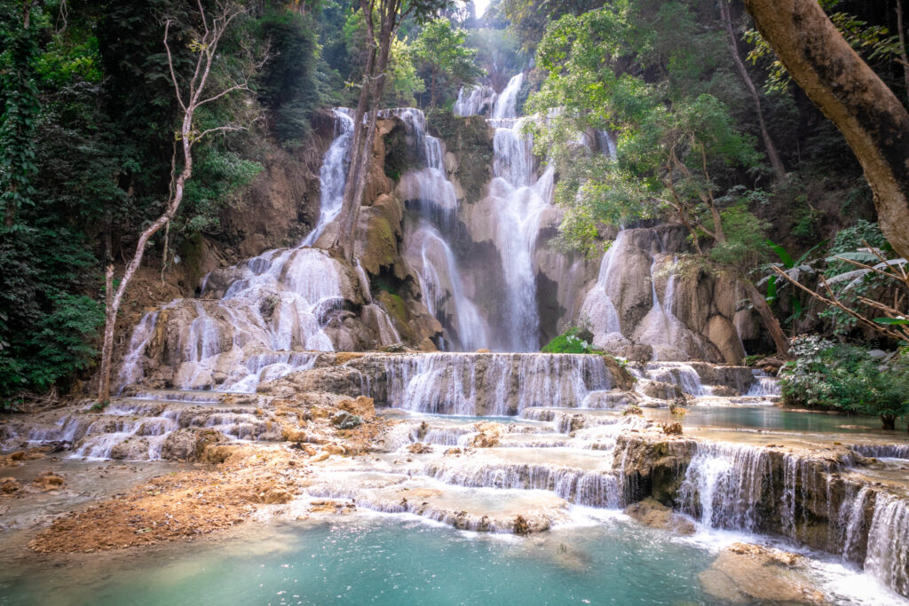 A multi-tiered waterfall falling into a turquoise pool surrounded by forest