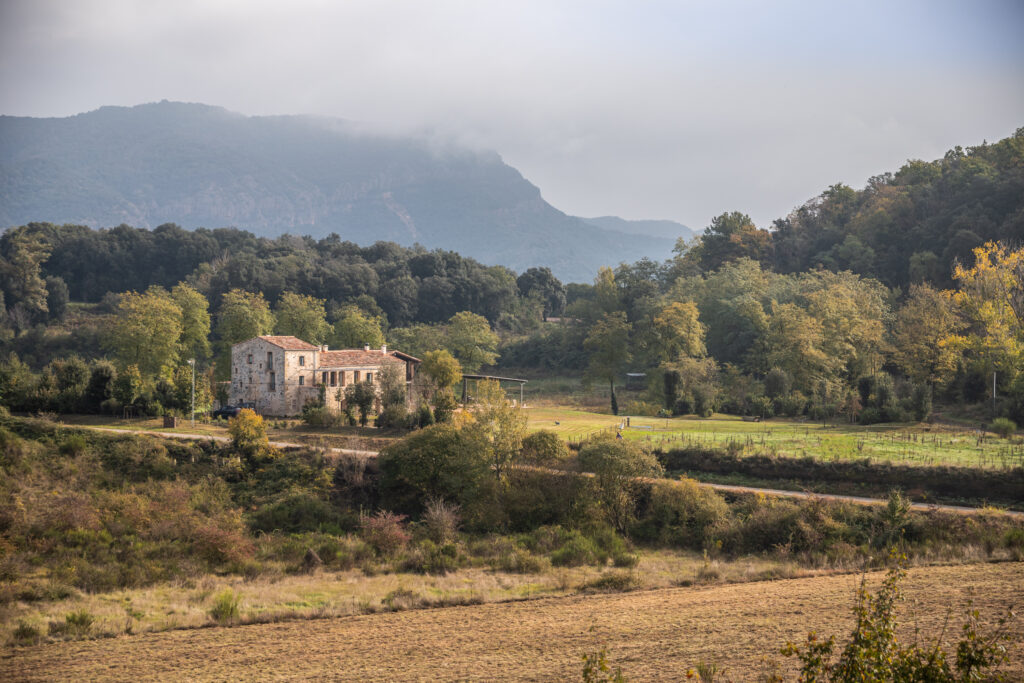 A stone farmhouse among green fields and forested hills
