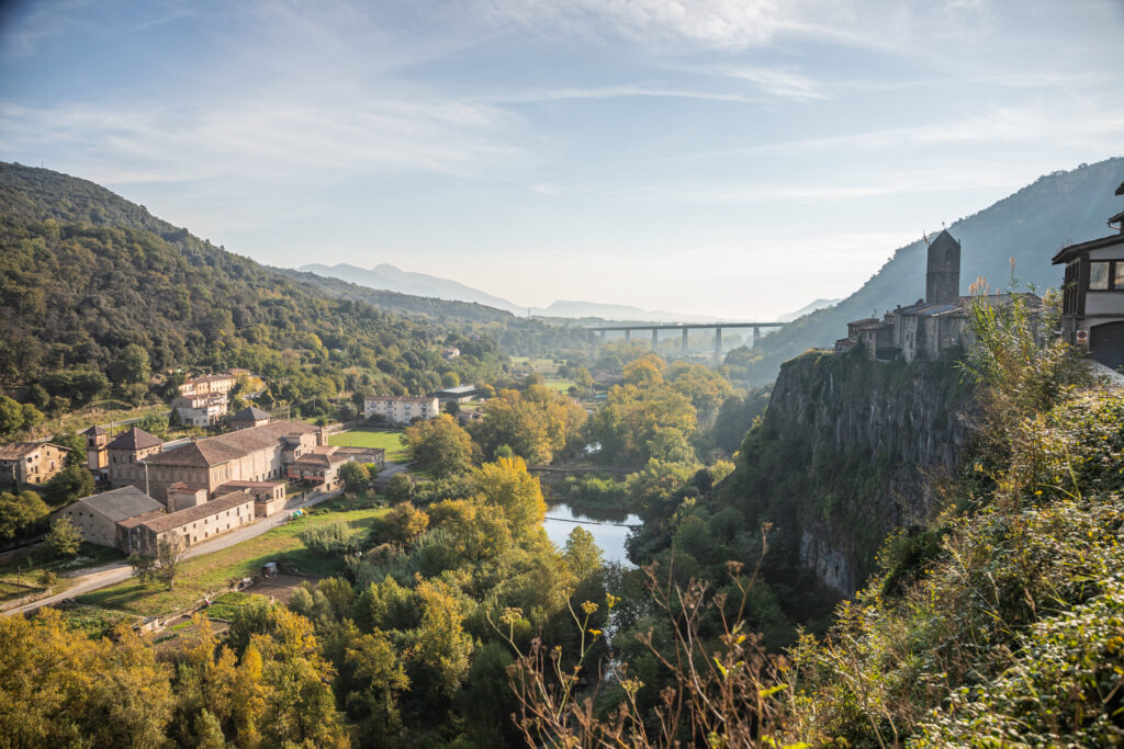 A valley seen from above, with a church on the hill to the right and a river flowing through the centre