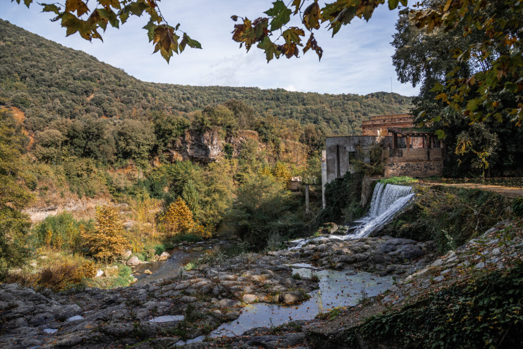 Looking out over a waterfall, stone and forest, with abandoned industrial buildings