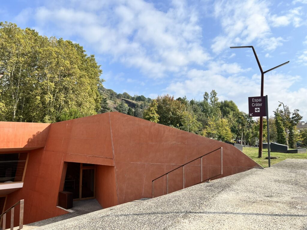 A red building going beneath the ground, with trees behind