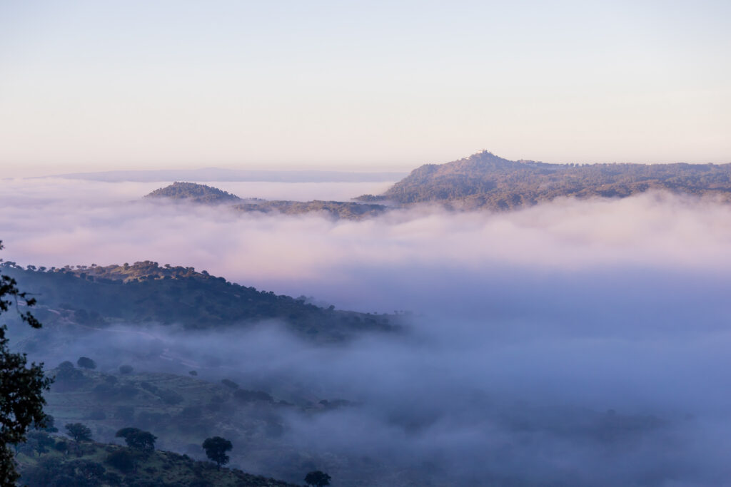 Morning fog in a valley with peaks and a clear sky above