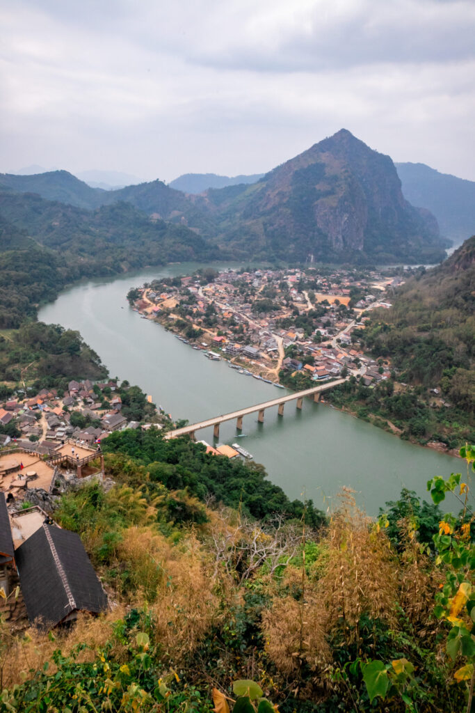 View from above of a town built on a river loop with steep mountains surrounding it and a bridge crossing the river