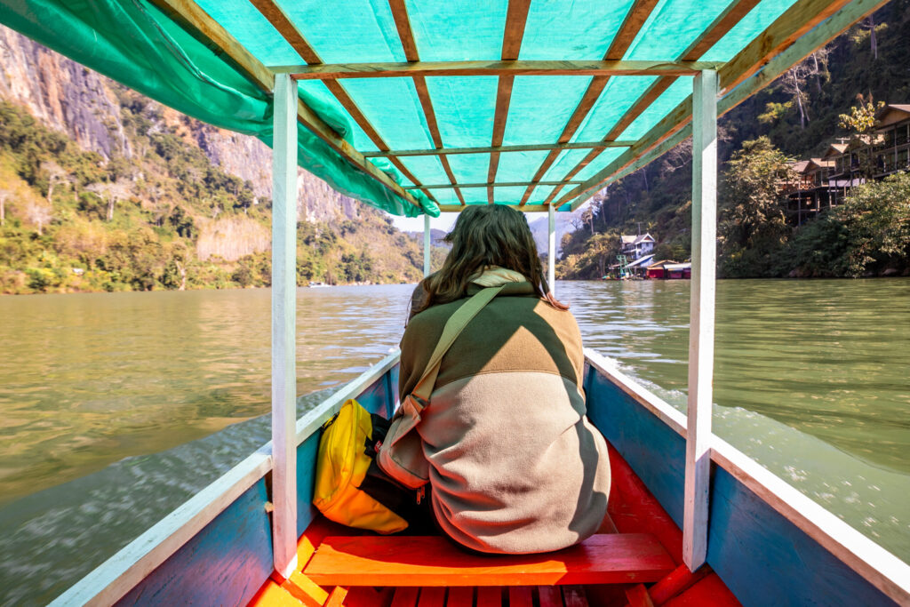 A girl sitting on a boat on a river in Laos