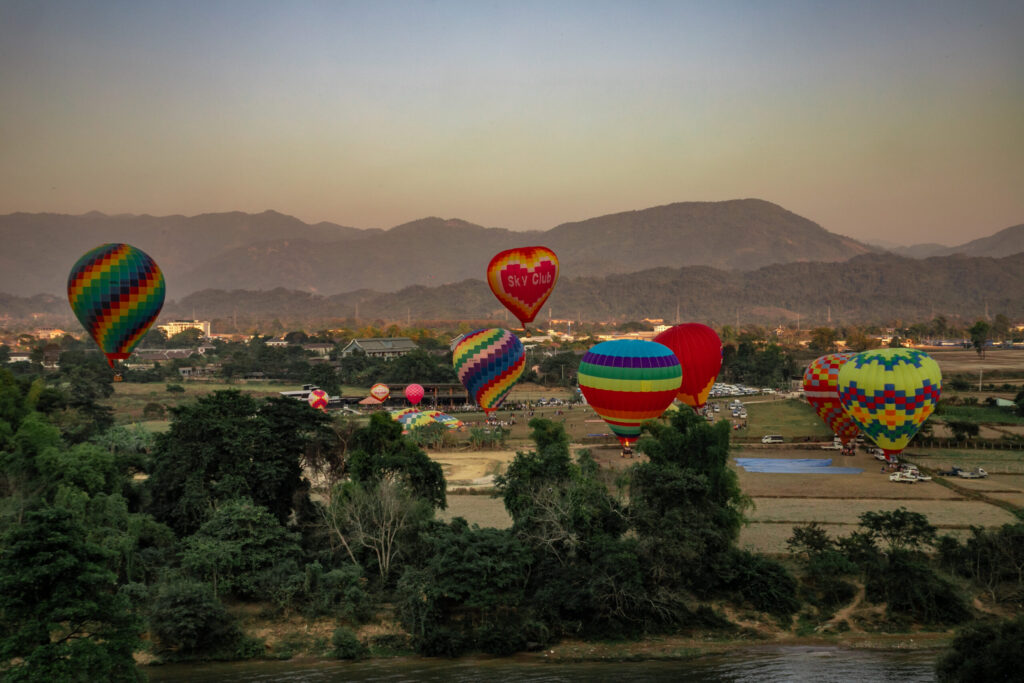 Hot air balloons taking off from a field in Vang Vieng, a popular stop on any Laos itinerary