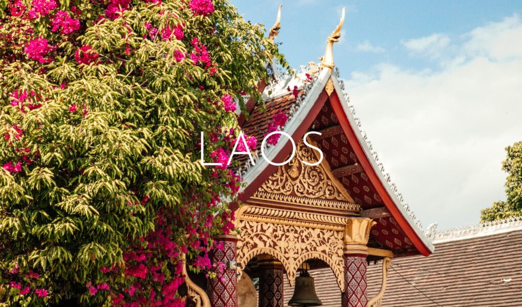 A decorative temple roof half-covered in greenery and pink flowers, overlaid with 'Laos' text