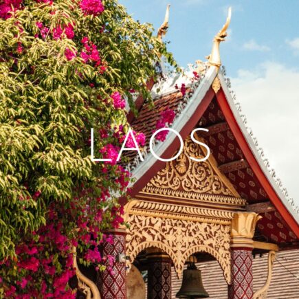 A decorative temple roof half-covered in greenery and pink flowers, overlaid with 'Laos' text