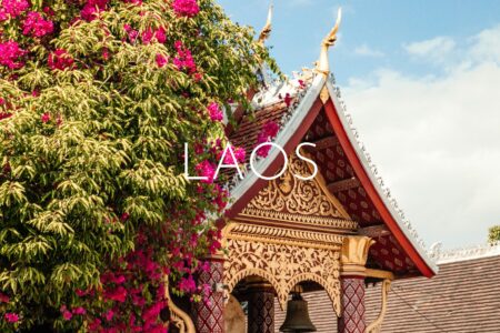 A decorative temple roof half-covered in greenery and pink flowers, overlaid with 'Laos' text